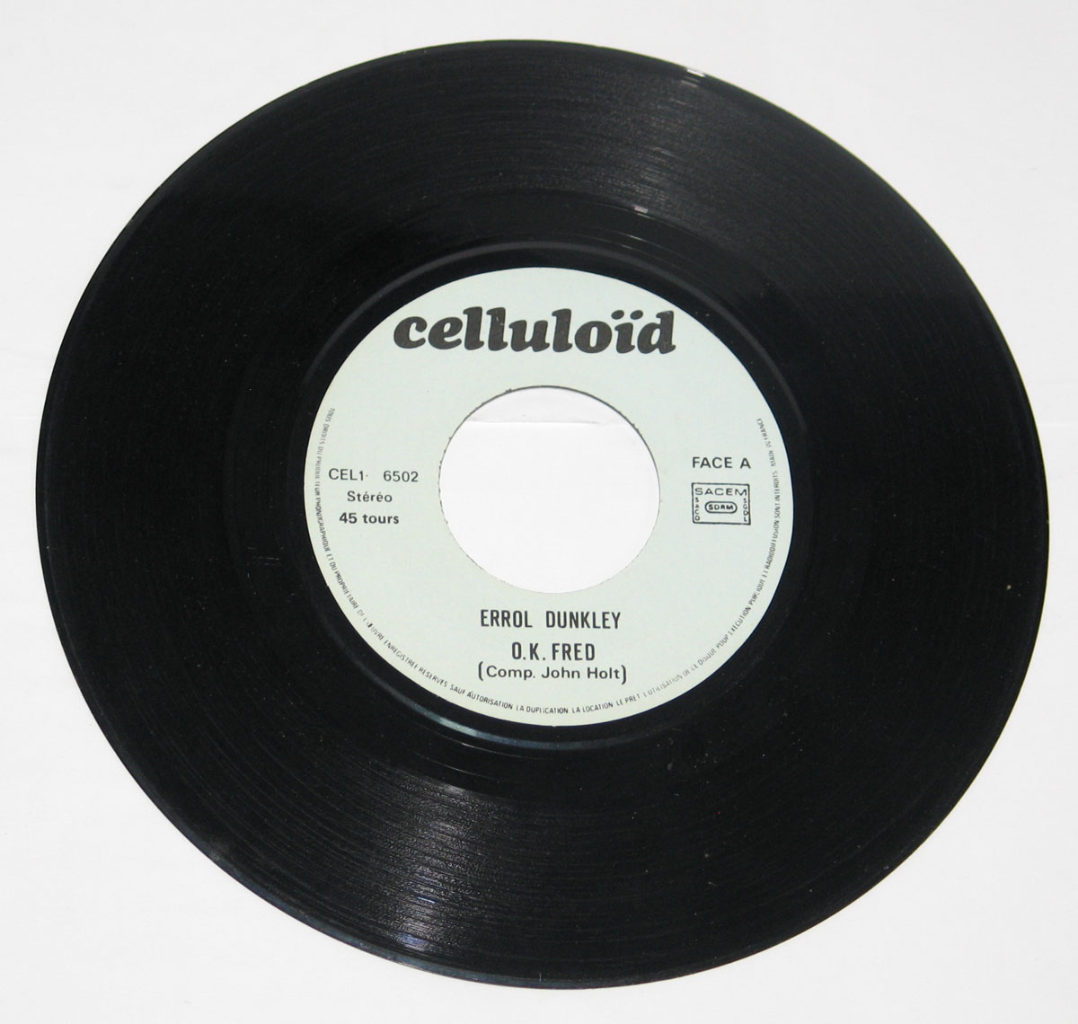 Side One of Errol Dunkley's 7 inch single 'OK Fred' on Celluloid label. White center label with black text, catalog number CEL1-6502, SACEM logo, and credit to composer John Holt. 45 RPM stereo pressing marked 'Face A'.